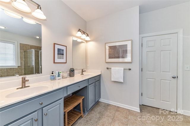 bathroom featuring a sink, baseboards, double vanity, and a shower stall