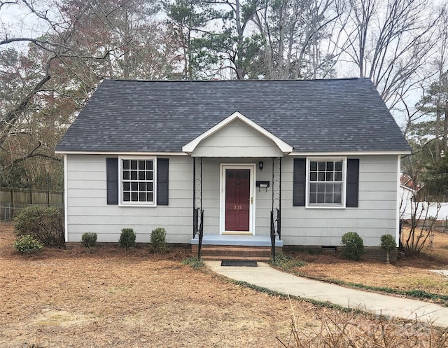 view of front facade with crawl space, roof with shingles, and fence