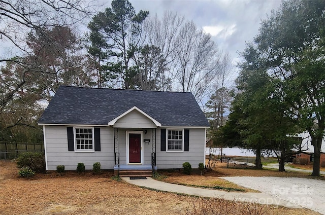 view of front facade with a shingled roof and fence