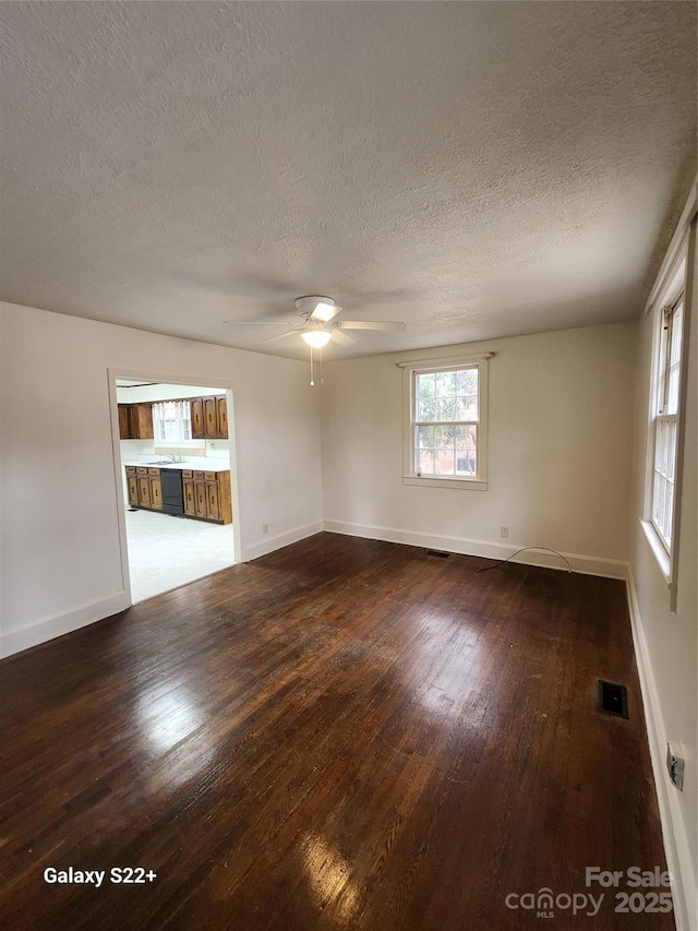 unfurnished living room featuring ceiling fan, hardwood / wood-style flooring, visible vents, and baseboards