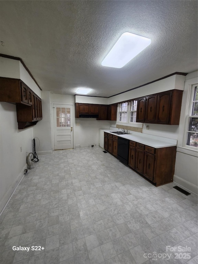 kitchen featuring dark brown cabinetry, baseboards, visible vents, dishwasher, and light floors