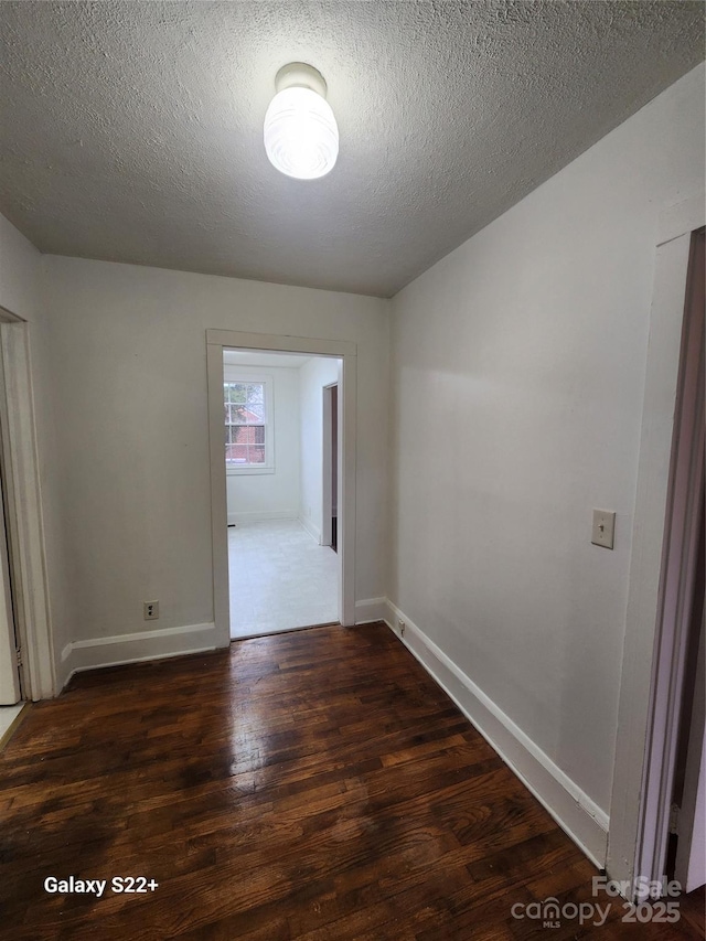 spare room featuring a textured ceiling, baseboards, and wood finished floors