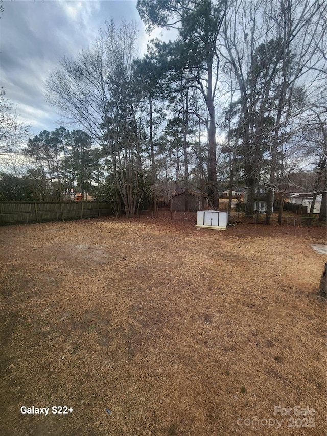 view of yard featuring a storage shed, an outdoor structure, and fence