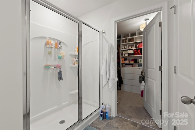 bathroom with stone finish flooring, a walk in closet, and a shower stall