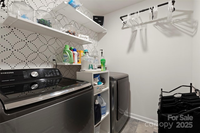 laundry room with laundry area, washing machine and dryer, baseboards, and wood finished floors