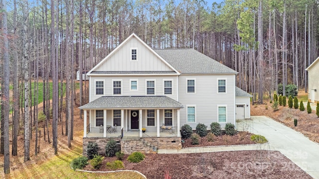 view of front of property with covered porch, board and batten siding, concrete driveway, and a shingled roof