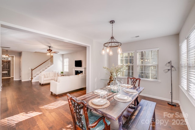 dining room with stairway, visible vents, baseboards, a fireplace, and dark wood-style flooring