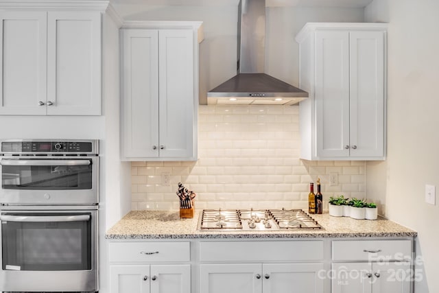 kitchen featuring white cabinets, appliances with stainless steel finishes, and wall chimney range hood