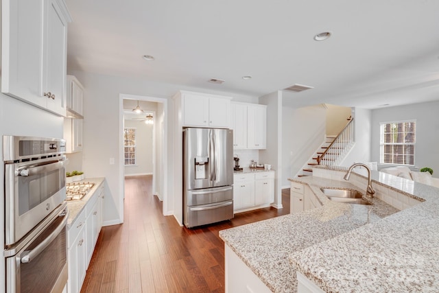 kitchen featuring visible vents, a sink, dark wood finished floors, appliances with stainless steel finishes, and white cabinets