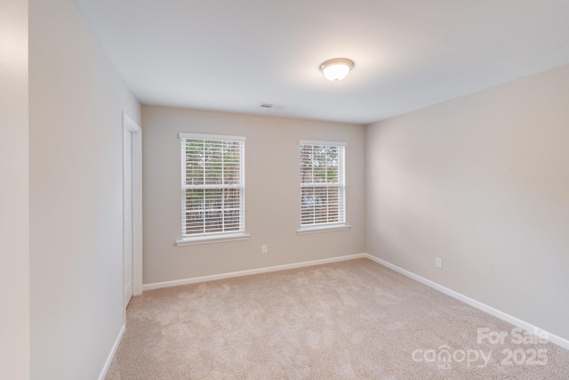 spare room with carpet flooring, visible vents, and baseboards