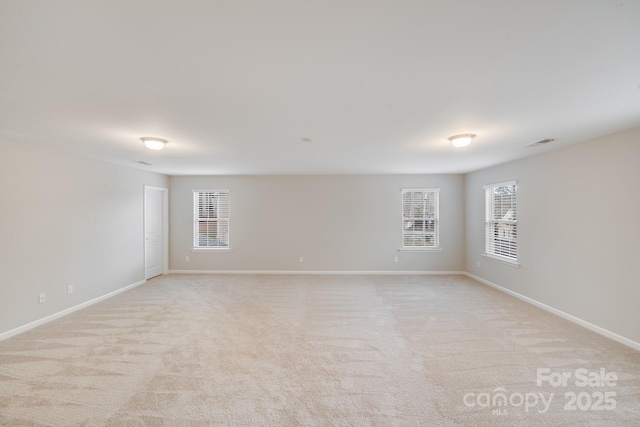 empty room featuring light carpet, visible vents, and baseboards