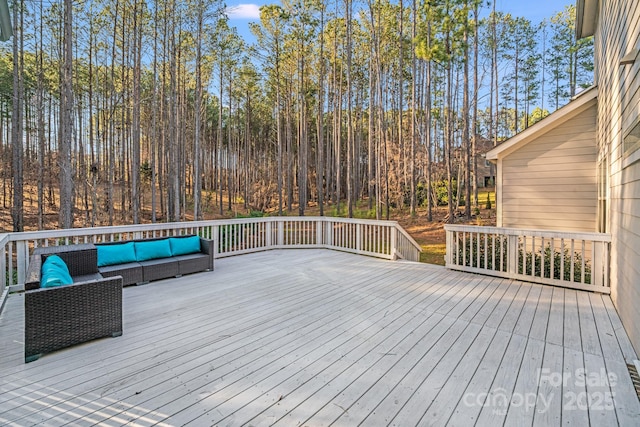 wooden terrace with an outdoor living space and a forest view