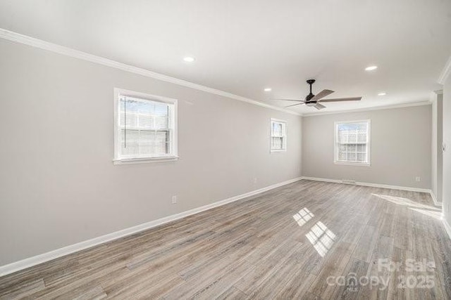 spare room with light wood-style floors, crown molding, and baseboards