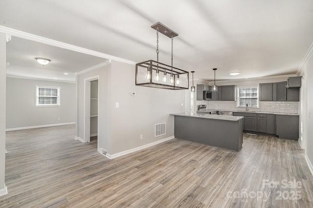 kitchen featuring gray cabinetry, a peninsula, visible vents, open floor plan, and light wood-type flooring