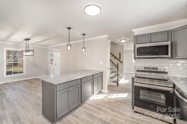 kitchen featuring stainless steel appliances, light wood-style floors, gray cabinets, tasteful backsplash, and crown molding