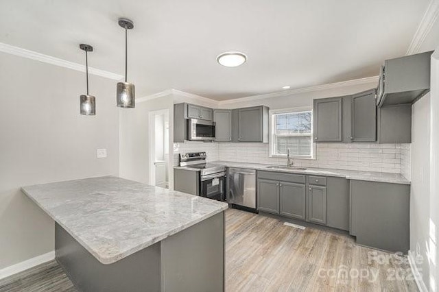 kitchen featuring a peninsula, stainless steel appliances, a sink, and gray cabinetry