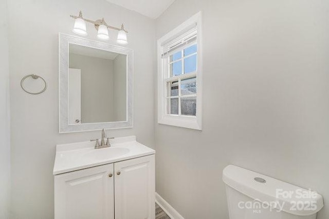 bathroom featuring toilet, vanity, and baseboards