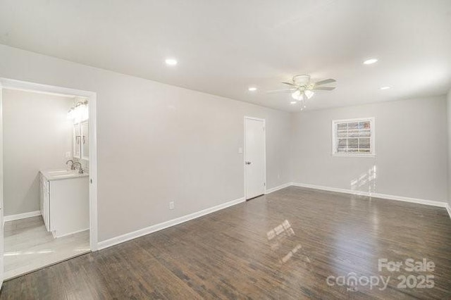 empty room with a sink, baseboards, wood finished floors, and recessed lighting