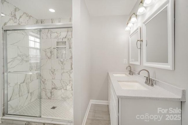 bathroom featuring a sink, a marble finish shower, and baseboards