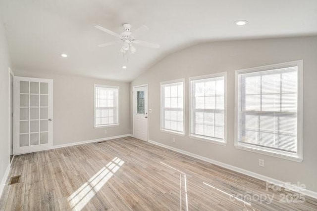 spare room featuring light wood finished floors, visible vents, a ceiling fan, vaulted ceiling, and baseboards