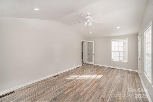 unfurnished room with baseboards, visible vents, vaulted ceiling, light wood-style floors, and recessed lighting