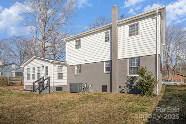 rear view of property with entry steps, a chimney, central AC, and a yard