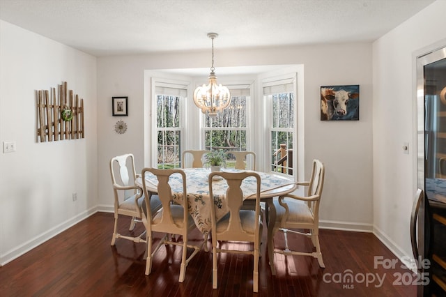 dining space with dark wood-type flooring, baseboards, and a chandelier