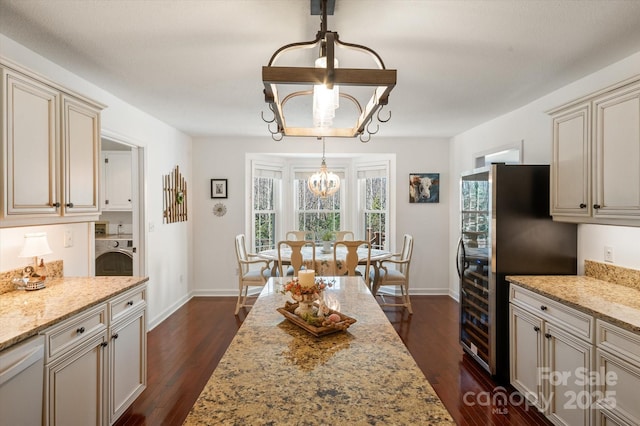 dining area with dark wood finished floors, washer / dryer, baseboards, and a chandelier