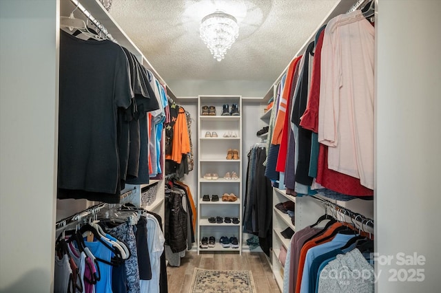 walk in closet featuring light wood-style floors and a chandelier