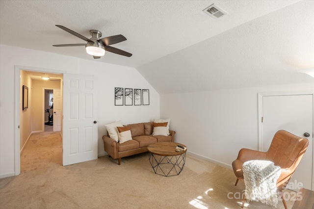 living room featuring baseboards, visible vents, vaulted ceiling, a textured ceiling, and light carpet