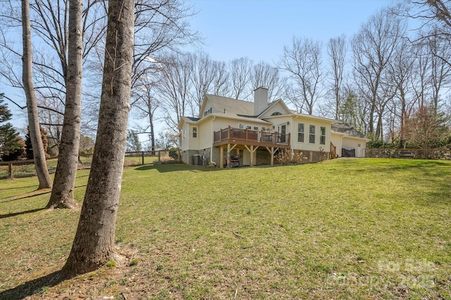 rear view of house with a wooden deck, an attached garage, a lawn, and a chimney