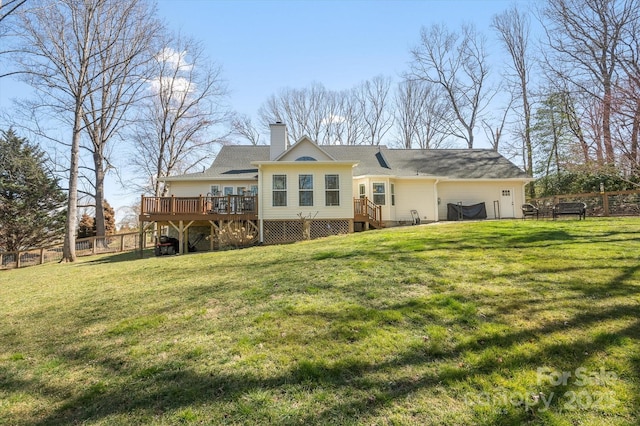 rear view of property with a lawn, a wooden deck, and fence