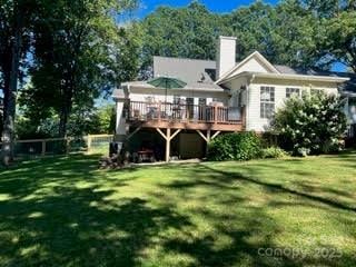 rear view of house with a wooden deck, a lawn, and a chimney