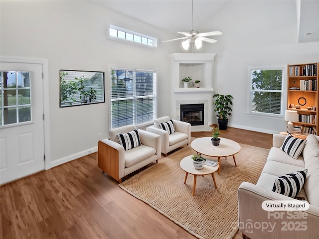 living area featuring high vaulted ceiling, a tile fireplace, plenty of natural light, and wood finished floors