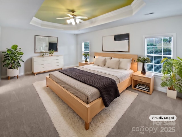 carpeted bedroom featuring a raised ceiling, visible vents, ornamental molding, ceiling fan, and baseboards