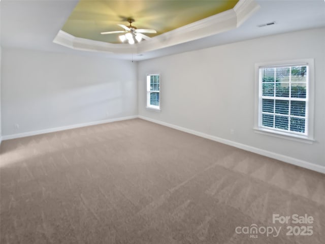 carpeted empty room featuring crown molding, a raised ceiling, ceiling fan, and baseboards