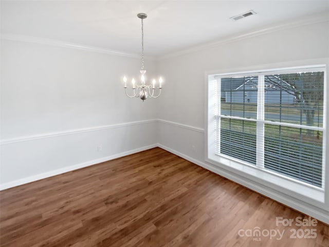 unfurnished dining area with visible vents, an inviting chandelier, ornamental molding, wood finished floors, and baseboards