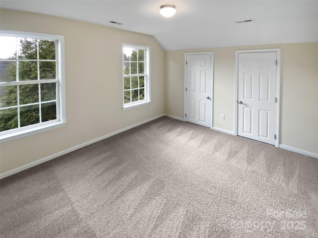 unfurnished bedroom featuring carpet floors, baseboards, visible vents, and vaulted ceiling