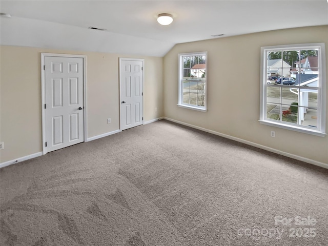 interior space featuring lofted ceiling, baseboards, visible vents, and carpet flooring