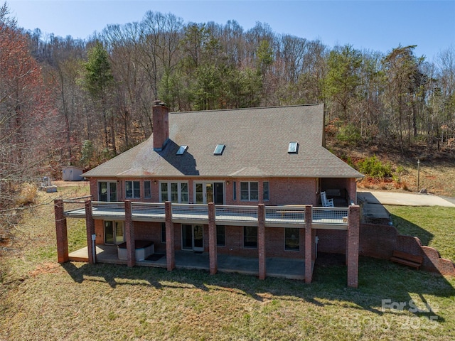 back of house with a patio, a lawn, brick siding, and a chimney