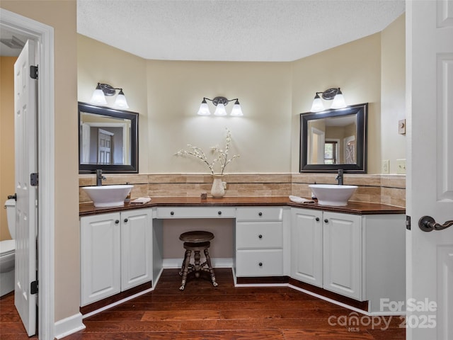 bathroom featuring double vanity, a textured ceiling, wood finished floors, and a sink