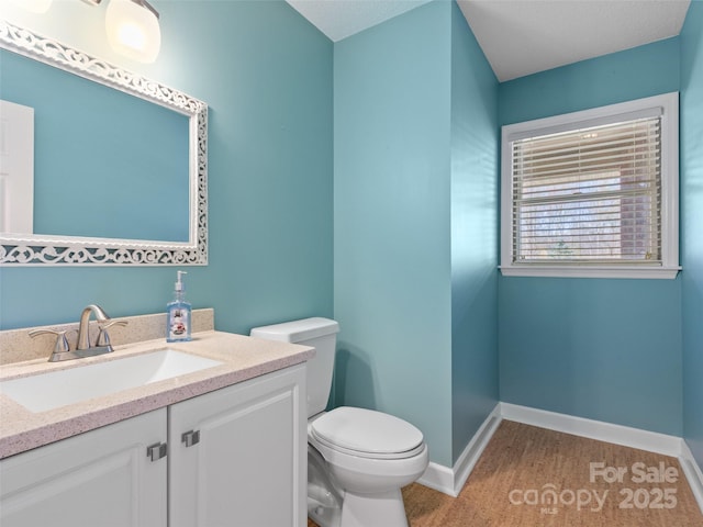 bathroom with toilet, vanity, and baseboards