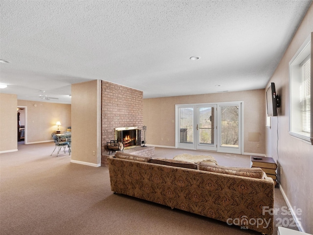 carpeted living room with ceiling fan, a fireplace, baseboards, and a textured ceiling