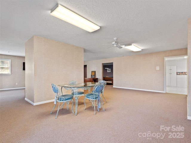 dining room with carpet flooring, a textured ceiling, baseboards, and ceiling fan