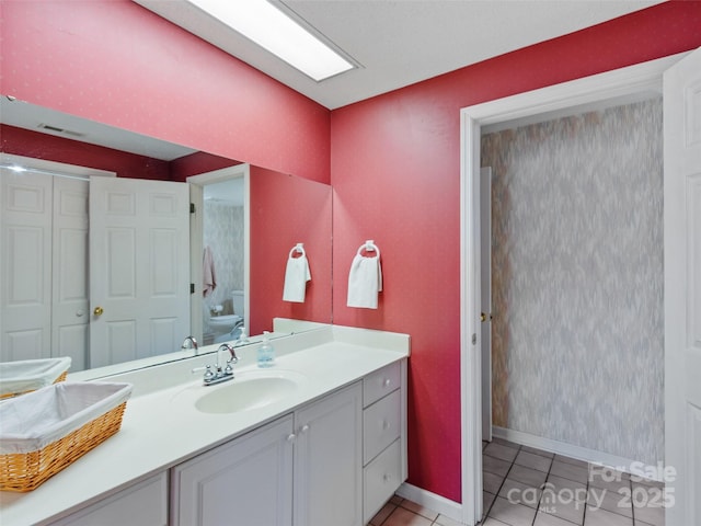 bathroom with vanity, baseboards, visible vents, tile patterned floors, and toilet