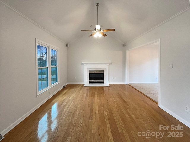 unfurnished living room with a ceiling fan, lofted ceiling, a fireplace with flush hearth, wood finished floors, and crown molding