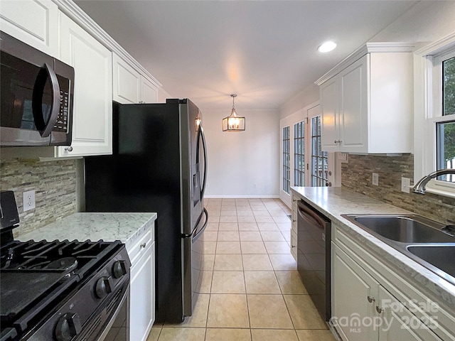 kitchen with light tile patterned floors, baseboards, white cabinets, stainless steel appliances, and a sink