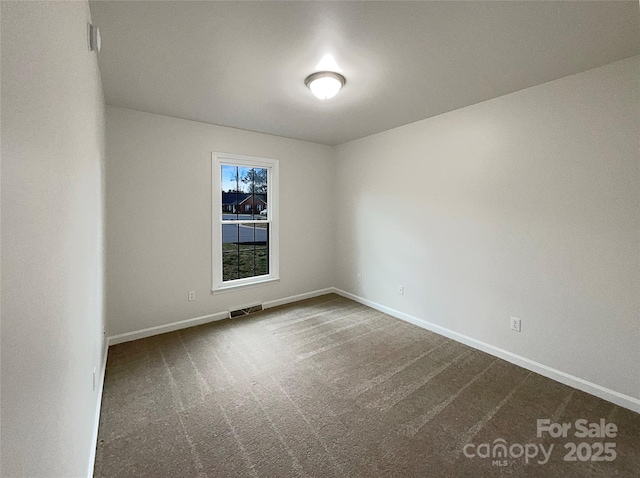 unfurnished room with dark colored carpet, visible vents, and baseboards