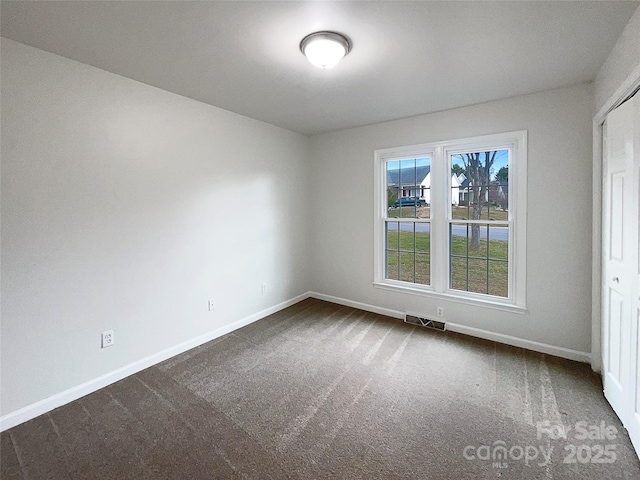 unfurnished room featuring baseboards, visible vents, and dark carpet