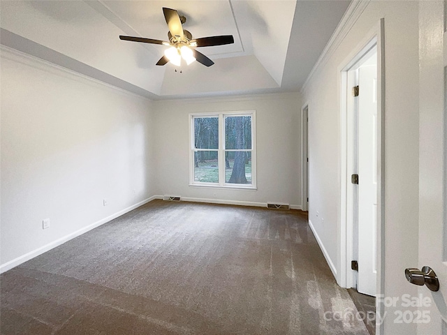 carpeted spare room with a tray ceiling, crown molding, visible vents, ceiling fan, and baseboards